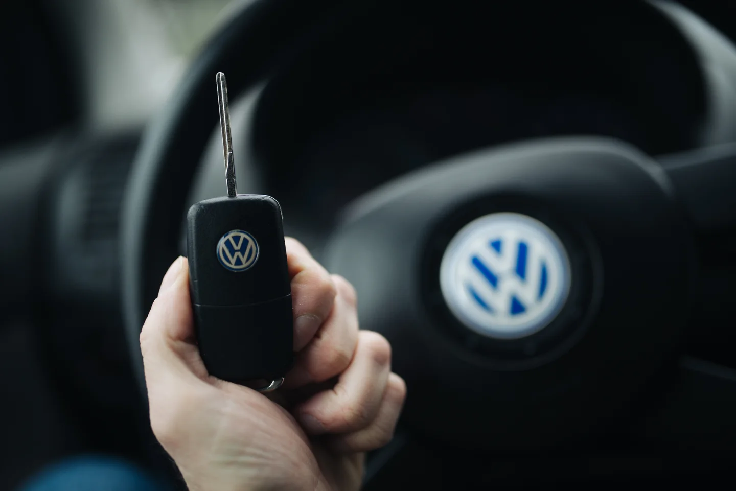 A real Volkswagen flip key held in front of a steering wheel